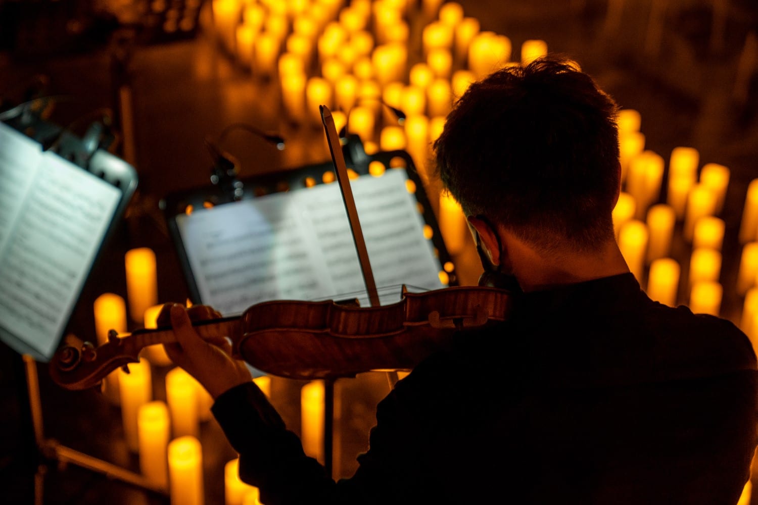 Violinist playing music surrounded by glowing candles