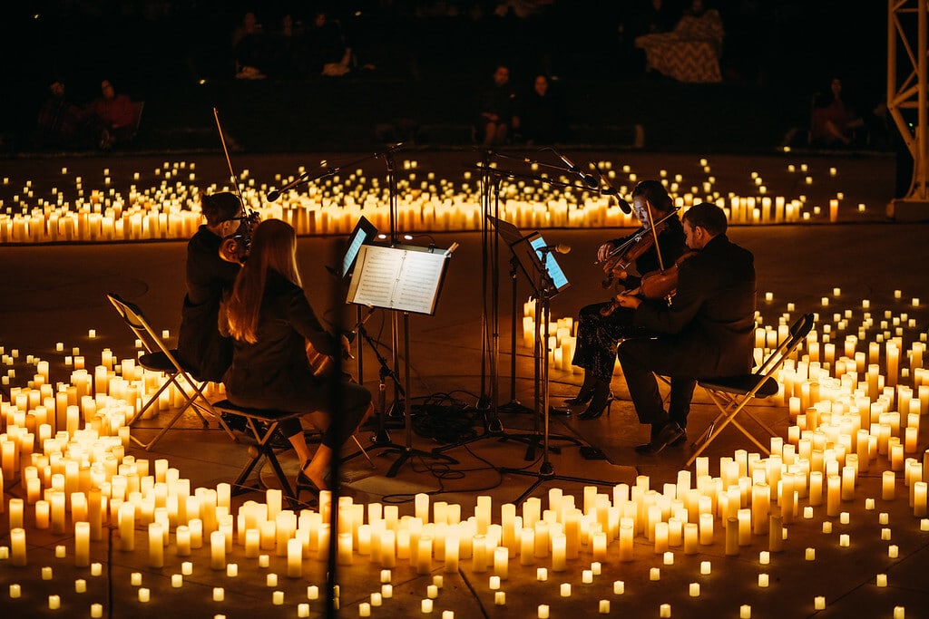 A string quartet plays music surrounding by flameless candles at a Fever candlelight concert.