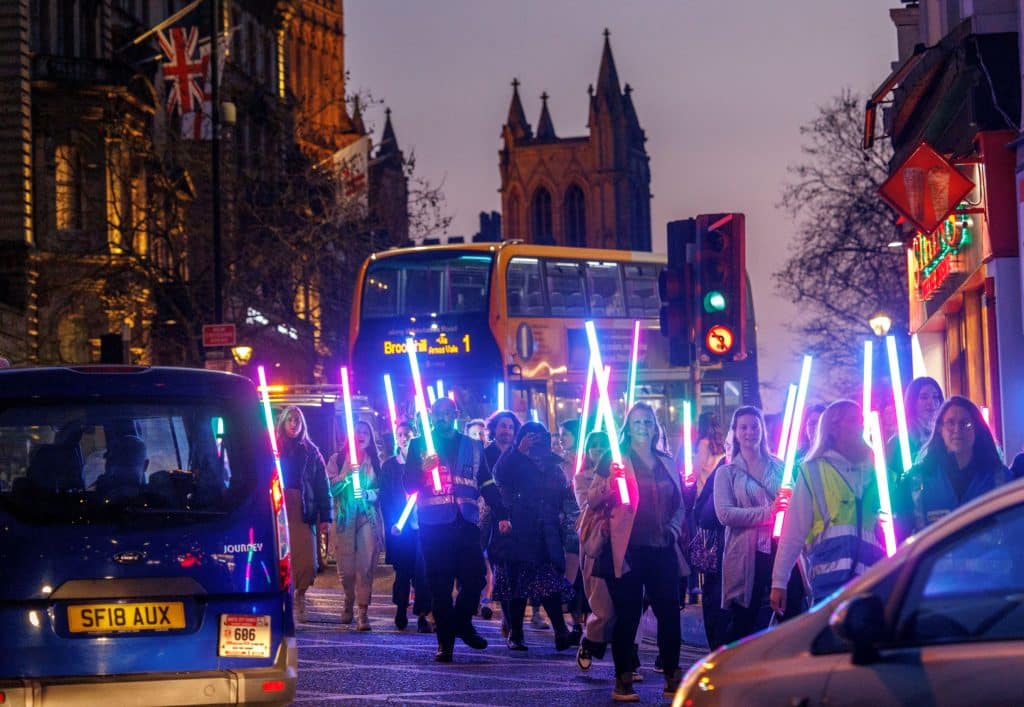 Women march through Bristol at night with glowsticks for Bristol Nights