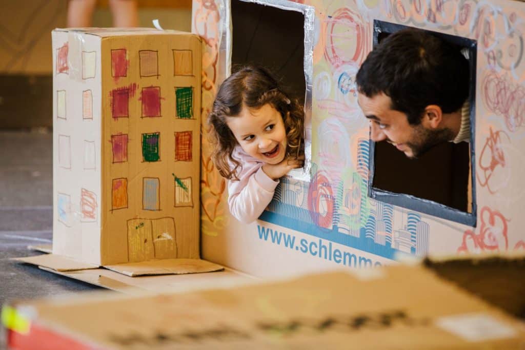 A child and man playing in a cardboard house