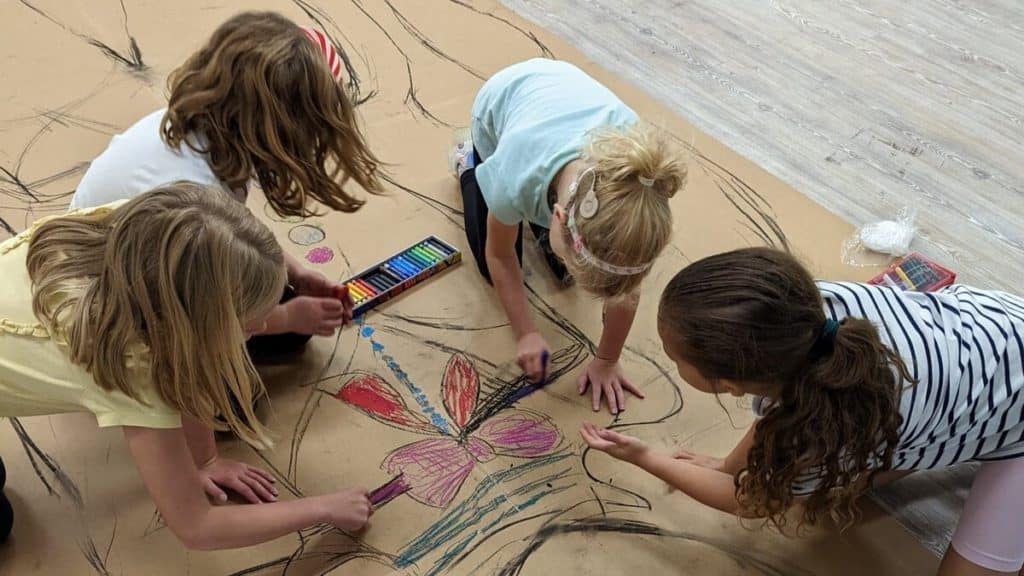 Four children drawing on cardboard