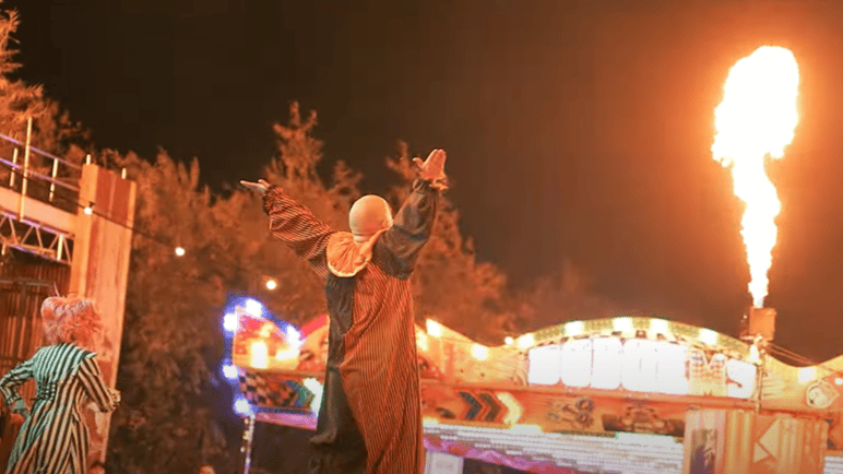 Two clowns looking on a flame of fire at a funfair for Halloween in Bristol