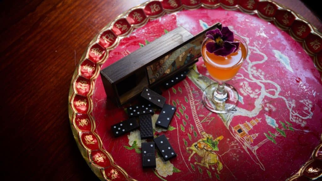 The Milk Thistle's Gyoen Tea House cocktail next to a game of dominoes