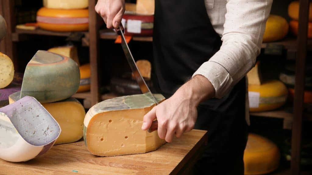 a worker cutting cheese in one of Bristol cheese shops