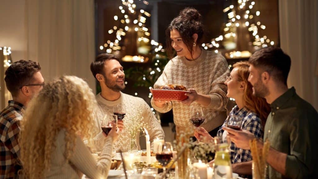 A group of people sat at a table serving Christmas dinner