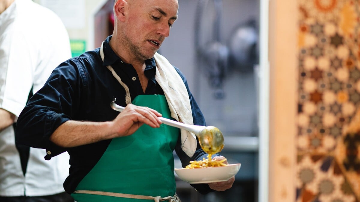 A chef at Pastan serving a bowl of vegan pasta