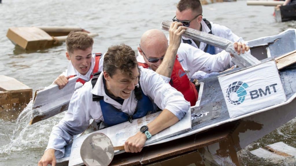 Four men trying to paddle as their boat sinks during the cardboard boat race for Bristol Harbour Festival