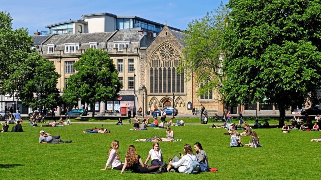 Sunbathers on College Green take advantage of the fine weather on a sunny spring day with The Lord Mayor's Chapel behind them