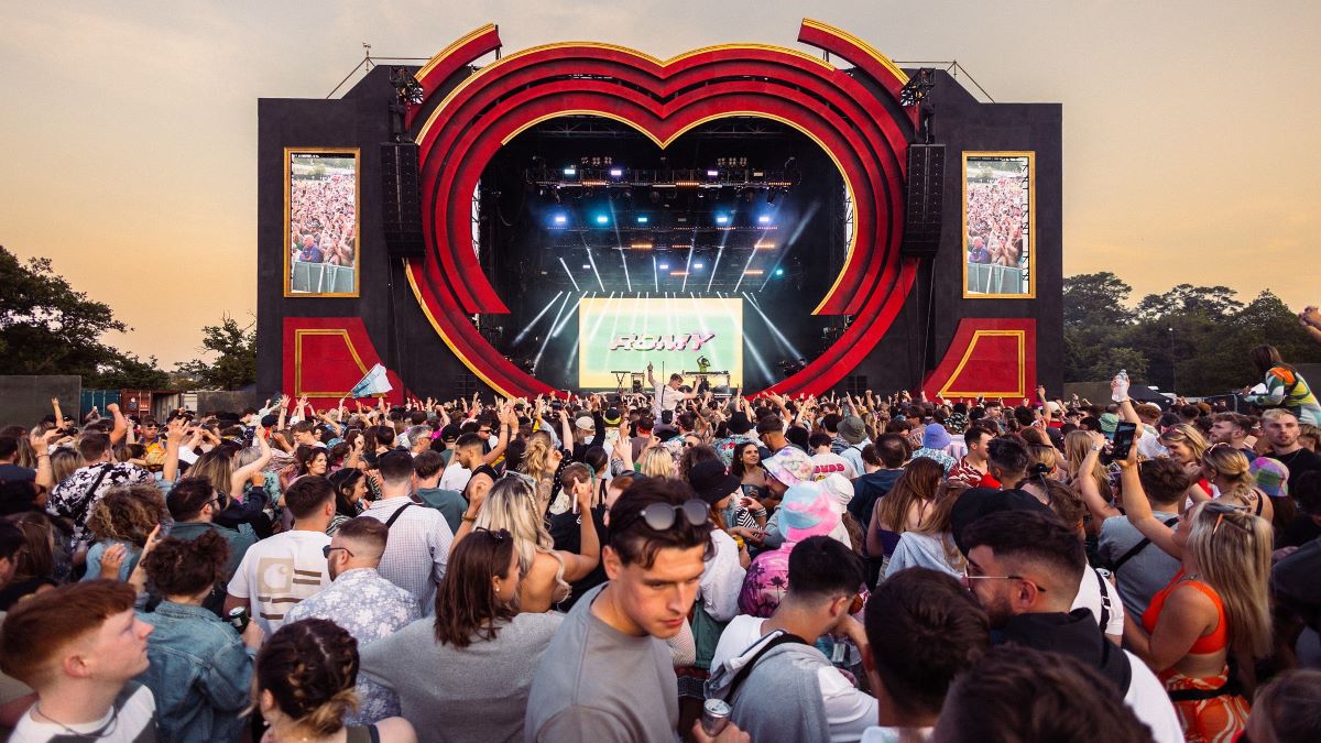 A crowd of people dancing in front of a colourful stage at Love Saves The Day, which will returning 2024